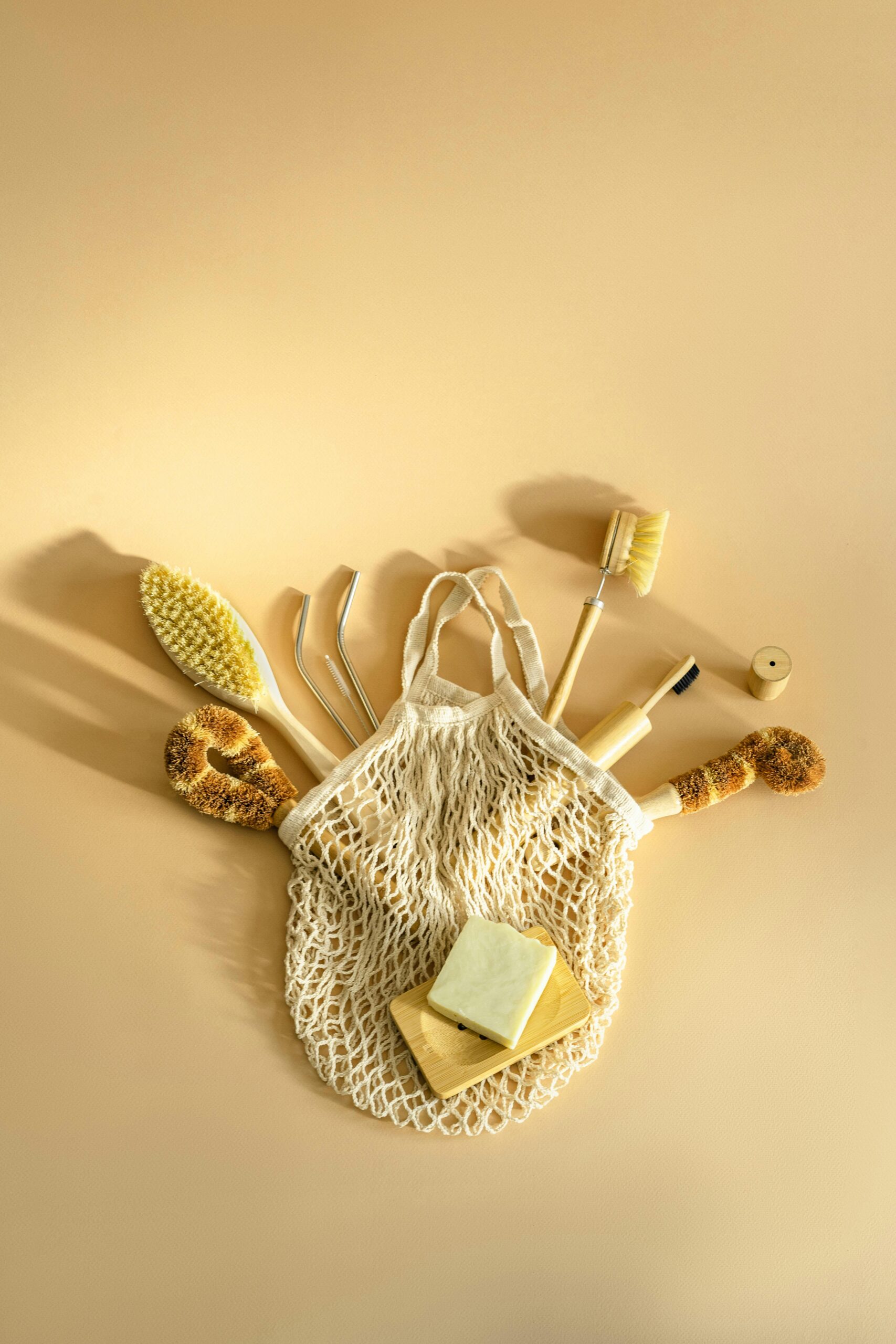 Minimalist flat lay of eco-friendly cleaning tools with mesh bag on neutral background.